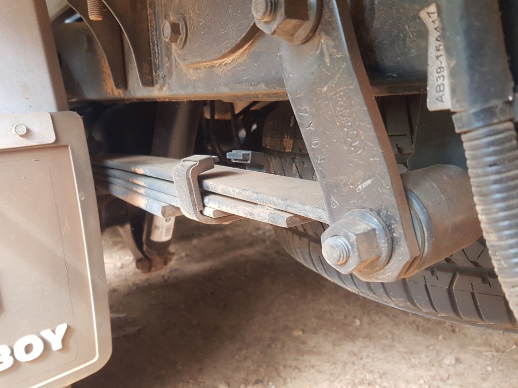 Close-up of inverted rear leaf springs on a tow vehicle, showing the visual signs of being over the rear axle weight limit.