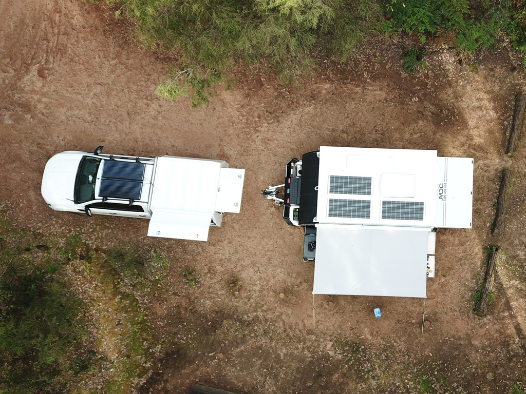 Aerial view of fixed caravan solar panels on a small off-road van and tow vehicle.